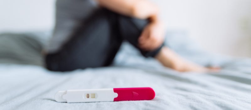 woman standing beside pregnancy test