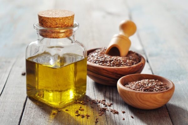 Sesame seeds and oil in bottle on wooden background